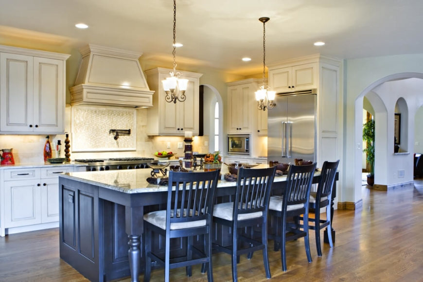 This extraordinary kitchen island grants a burst of contrast to its respective room, with a dark stained wood structure and bright marble countertop. The extended countertop space allows for in-kitchen dining, with a set of matching wood bar stools tucked in. This extraordinary kitchen island grants a burst of contrast to its respective room, with a dark stained wood structure and bright marble countertop. The extended countertop space allows for in-kitchen dining, with a set of matching wood bar stools tucked in.