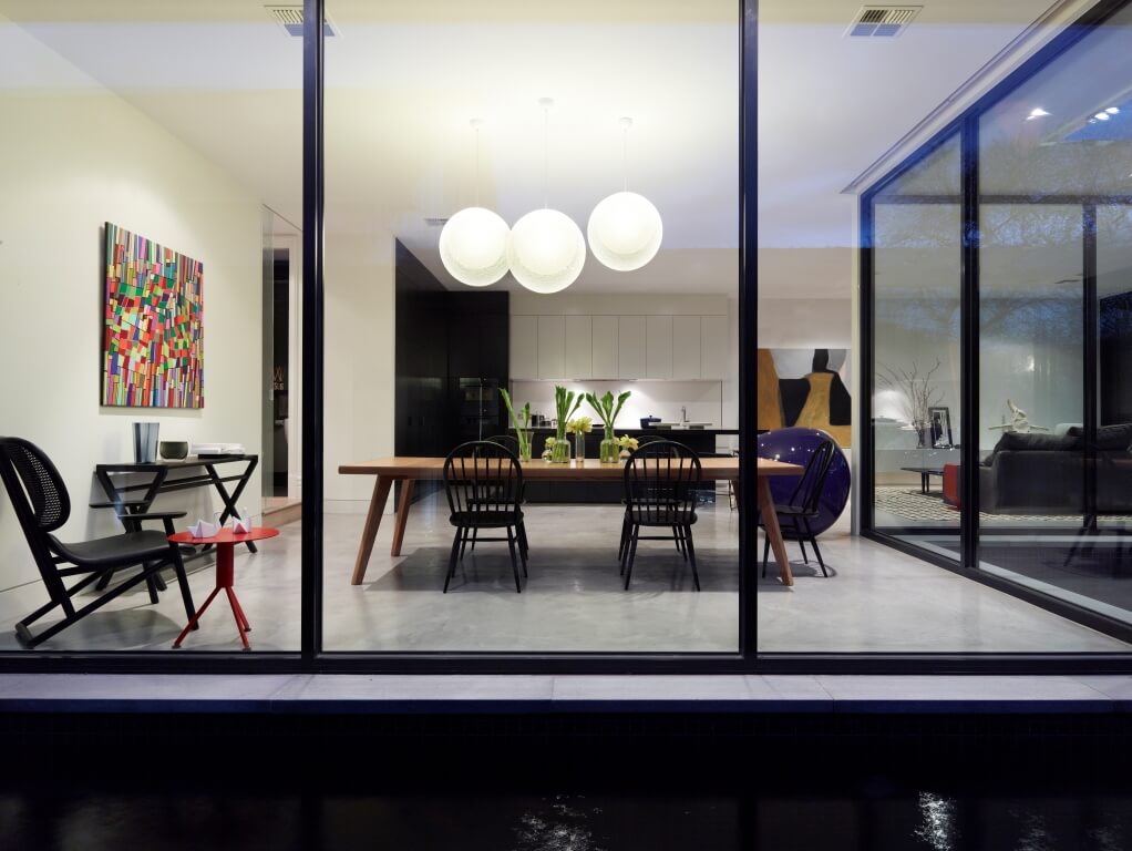 A dining room designed with huge pendant lights and a colorful abstract canvas placed over the buffet table. It boasts a wide space and high ceiling.