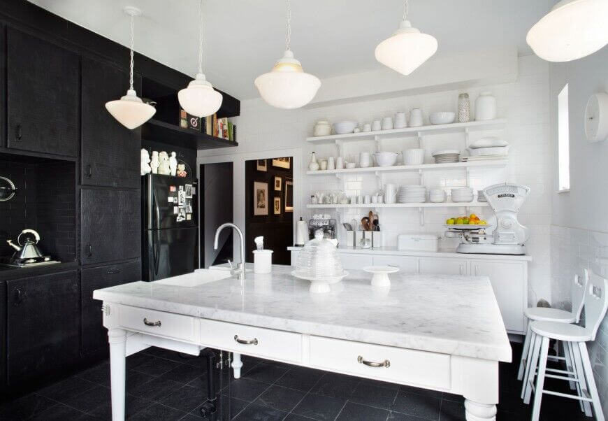 White and black strike an amazing contrast in the design of this kitchen. Ebony cabinets and backsplash, along with appliances and the tile floor, are mixed with an all-white marble island, open shelving, and walls. White and black strike an amazing contrast in the design of this kitchen. Ebony cabinets and backsplash, along with appliances and the tile floor, are mixed with an all-white marble island, open shelving, and walls.