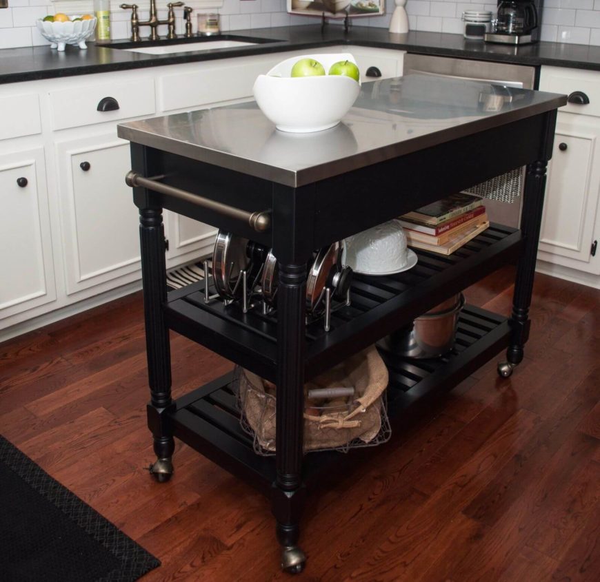 Our final kitchen island design is a unique take on the entire concept, with a slim frame and casters built into the legs for portability. This allows for dynamic placement and extraordinary utility. The black wood frame and stainless steel countertop make for a very sharp, modern appearance in this kitchen with hardwood flooring and white cabinetry. Our final kitchen island design is a unique take on the entire concept, with a slim frame and casters built into the legs for portability. This allows for dynamic placement and extraordinary utility. The black wood frame and stainless steel countertop make for a very sharp, modern appearance in this kitchen with hardwood flooring and white cabinetry.