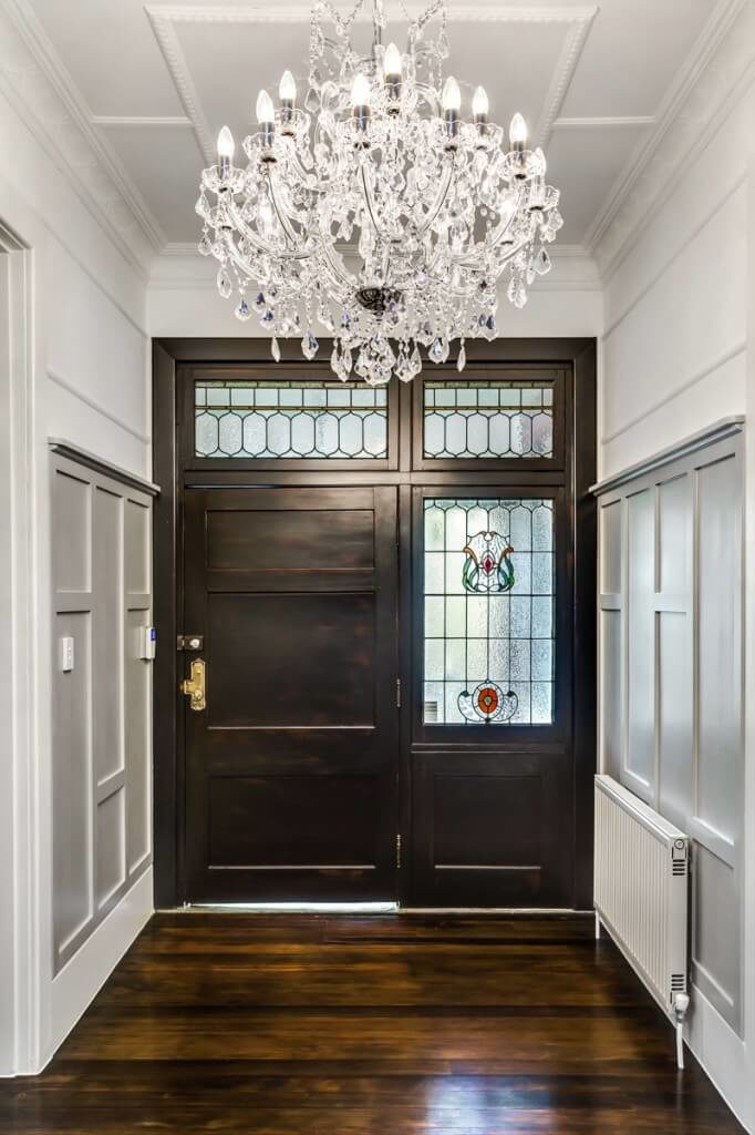 Pale paneled walls and a stunning crystal chandelier balance the dappled tones of the beautiful wood flooring and the deep wood of the front door. Gorgeous stained glass windows stand sentry around the broad front door. Pale paneled walls and a stunning crystal chandelier balance the dappled tones of the beautiful wood flooring and the deep wood of the front door. Gorgeous stained glass windows stand sentry around the broad front door.