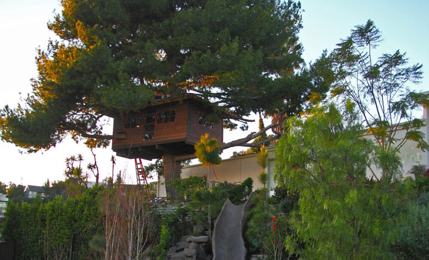 This spacious treehouse is built into an enormous tree. A faux stone slide is built into the hillside as well to create an adventure play area. This spacious treehouse is built into an enormous tree. A faux stone slide is built into the hillside as well to create an adventure play area.