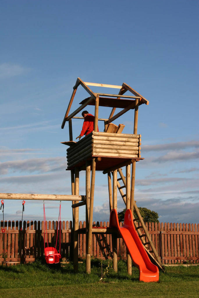 This playset, when finished, will have a log-cabin style atmosphere, a large, sturdy swingset, and a slide, in addition to the tall lookout tower. This playset, when finished, will have a log-cabin style atmosphere, a large, sturdy swingset, and a slide, in addition to the tall lookout tower.