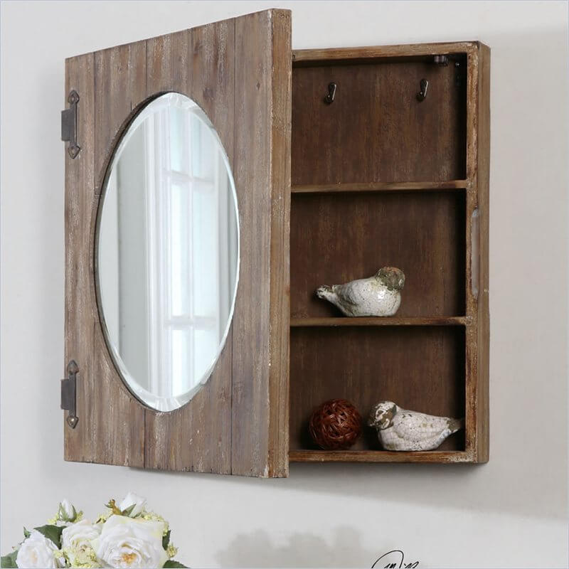 A beveled oval mirror is set into a rustic frame with iron hinges. The inside is filled with shelves and small hooks, which gives you a variety of options. A beveled oval mirror is set into a rustic frame with iron hinges. The inside is filled with shelves and small hooks, which gives you a variety of options.