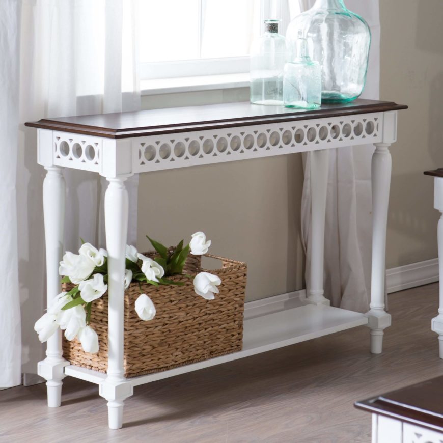 Delicate circles in a repeating pattern adds elegance to this white and wood console table. A lower shelf provides extra storage for purses, or even shoes. The beveled top adds even more elegance to the design. Delicate circles in a repeating pattern adds elegance to this white and wood console table. A lower shelf provides extra storage for purses, or even shoes. The beveled top adds even more elegance to the design.