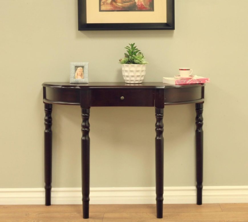 This half-circle table has a single drawer and is in a rich dark wood. The bowed design is sleek and delicate, with long, slim legs. This half-circle table has a single drawer and is in a rich dark wood. The bowed design is sleek and delicate, with long, slim legs.