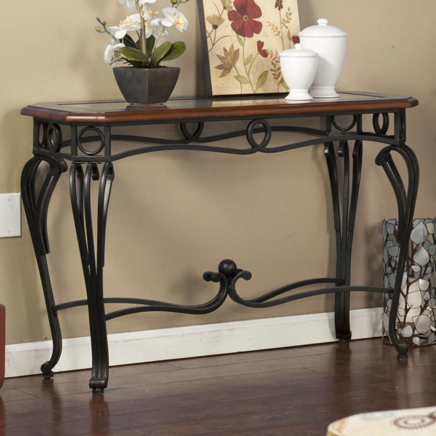 The swirls and curves of the wrought iron frame are incredibly elegant, adding to the charm of the wood-framed glass top. All together, this table makes for a stunning display item. The swirls and curves of the wrought iron frame are incredibly elegant, adding to the charm of the wood-framed glass top. All together, this table makes for a stunning display item.
