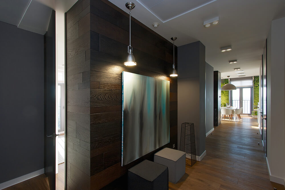 An entryway designed with a lovely gradient painting on an accent wood plank wall illuminated by a pair of pendant lights. It includes a black and white cube stools along with an industrial decor.
