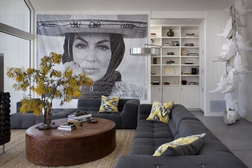 An enormous print takes up almost an entire wall, drawing attention from the solid charcoal gray sectional sofa. Light greens add a pop of color. An enormous print takes up almost an entire wall, drawing attention from the solid charcoal gray sectional sofa. Light greens add a pop of color.
