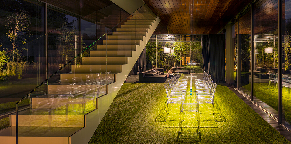 Marvelous dining room that can give you a feel of an al fresco dining. It has a glass table and chairs sitting on the faux grass carpet.