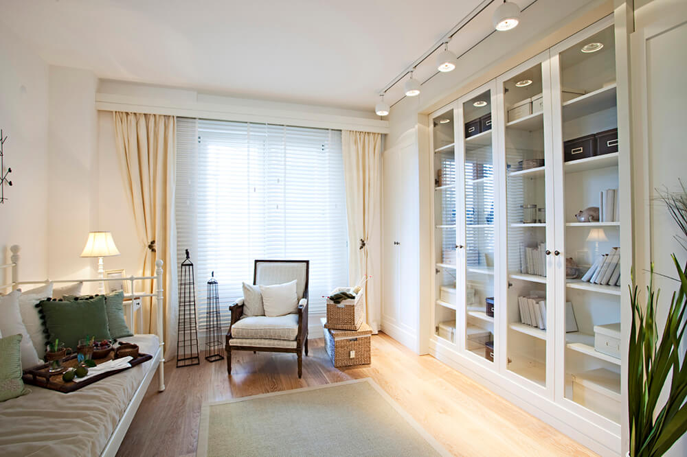This chic bedroom offers white multiple bookshelves protected by glass doors lighted by track lights.