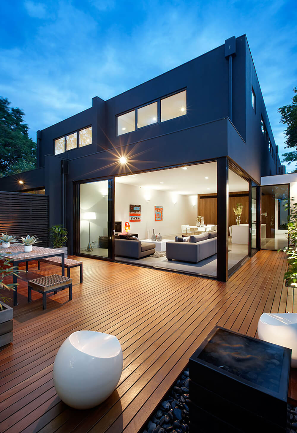 This deck features classy seats and a dining table set along with some plants on the side.