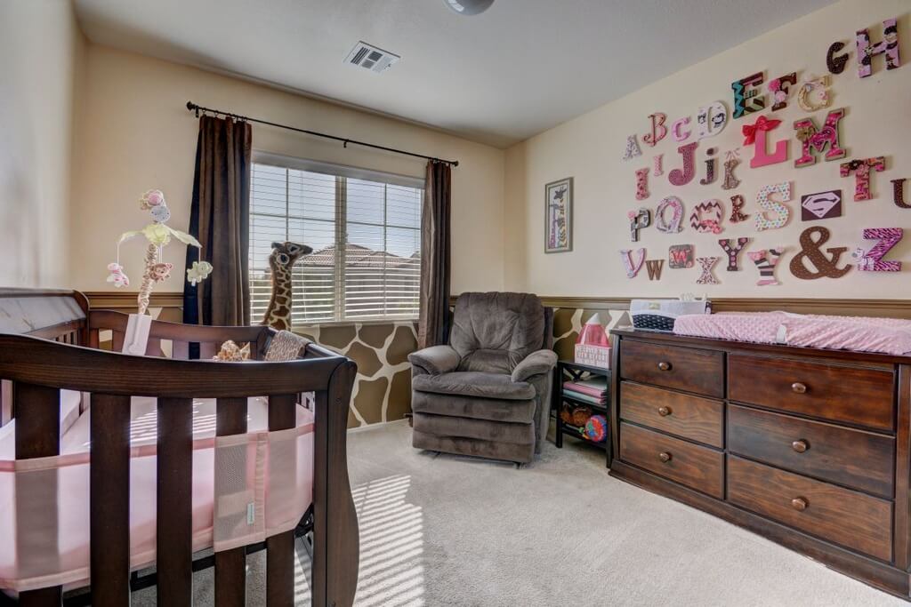 Nursery room with pink letters decorations on the wall and a gray carpet flooring.