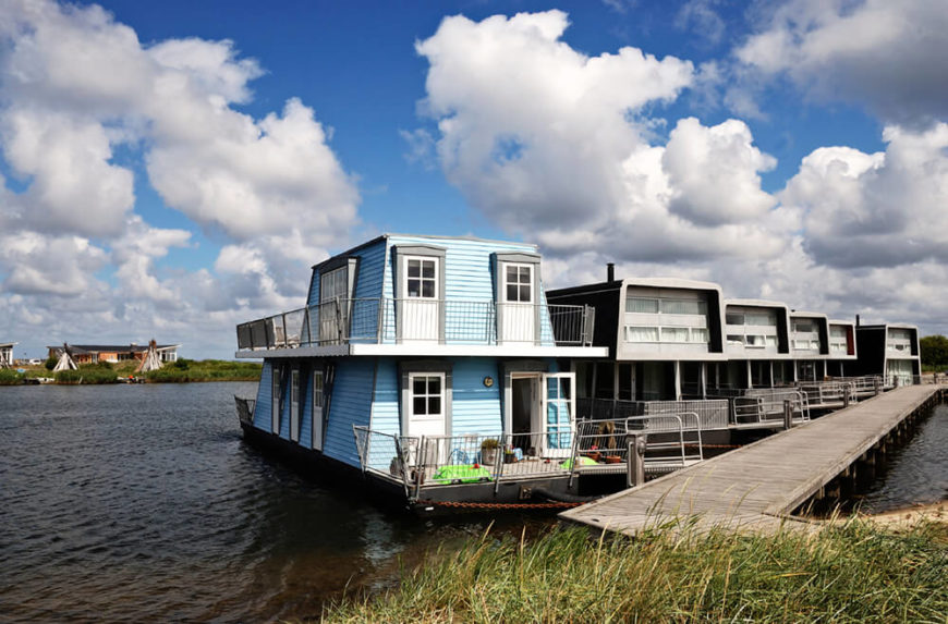 A lovely blue houseboat moored off of a large dock along side many other permanent houseboat homes. A lovely blue houseboat moored off of a large dock along side many other permanent houseboat homes.
