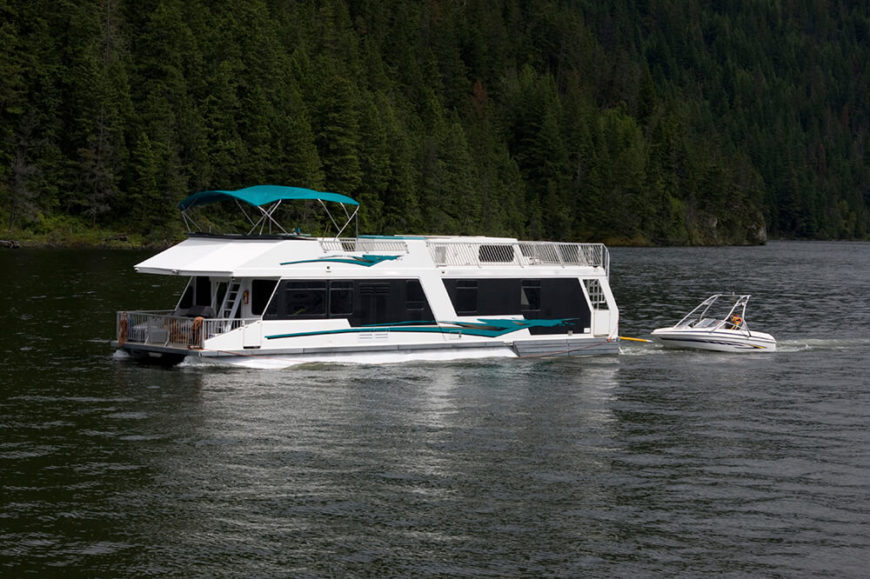 A sleek houseboat with a large upper deck and large tinted windows to preserve privacy while still allowing the owners to view the landscape. A sleek houseboat with a large upper deck and large tinted windows to preserve privacy while still allowing the owners to view the landscape.