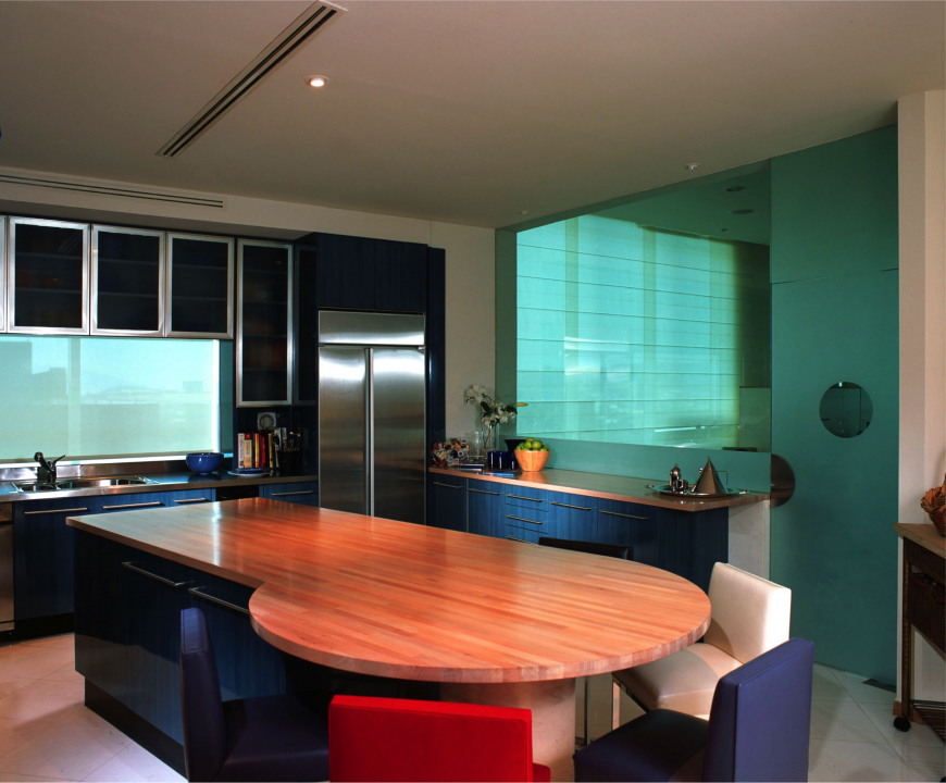 Color is a key component in to this kitchen design. Navy blue cabinets is complemented by the frosted blue glass of the accent wall. The natural wood counter tops break up the dark colors of the room and more pops of color are added in the leather accent chairs placed around the end of the island. Color is a key component in to this kitchen design. Navy blue cabinets is complemented by the frosted blue glass of the accent wall. The natural wood counter tops break up the dark colors of the room and more pops of color are added in the leather accent chairs placed around the end of the island.