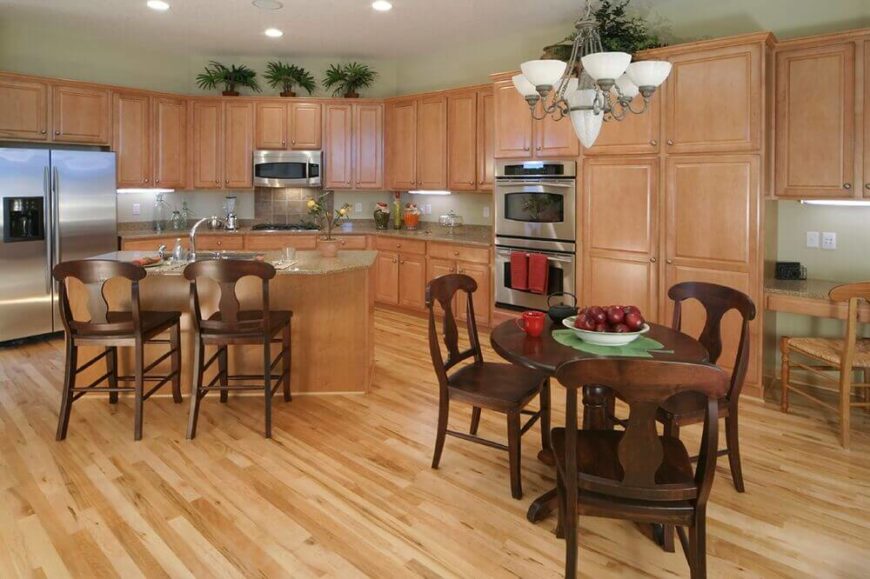 Dark stain on the wood of the chairs and table help it to stand out against the backdrop of the natural wood cabinets. This color is broken up by pale, sage green walls and the inclusion of plant life to highlight the use of green even more. A tile backsplash picks out different hues found in the granite countertop. Dark stain on the wood of the chairs and table help it to stand out against the backdrop of the natural wood cabinets. This color is broken up by pale, sage green walls and the inclusion of plant life to highlight the use of green even more. A tile backsplash picks out different hues found in the granite countertop.