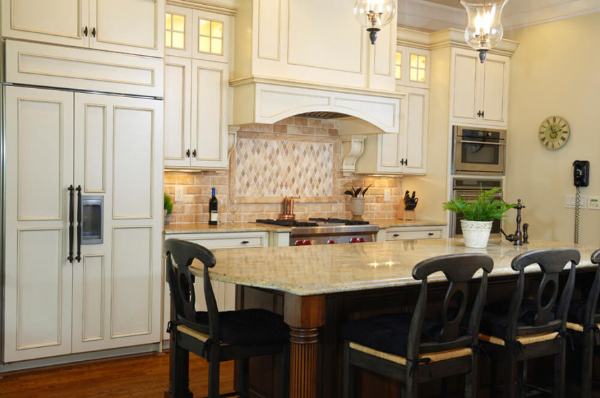 To balance the creamy, off-white cabinets, a dark wood island and even darker chairs were introduced to the room. This design element helps to ground the space and keep it from feeling too bright while also offering visual interest in a drastic change in colors. To balance the creamy, off-white cabinets, a dark wood island and even darker chairs were introduced to the room. This design element helps to ground the space and keep it from feeling too bright while also offering visual interest in a drastic change in colors.