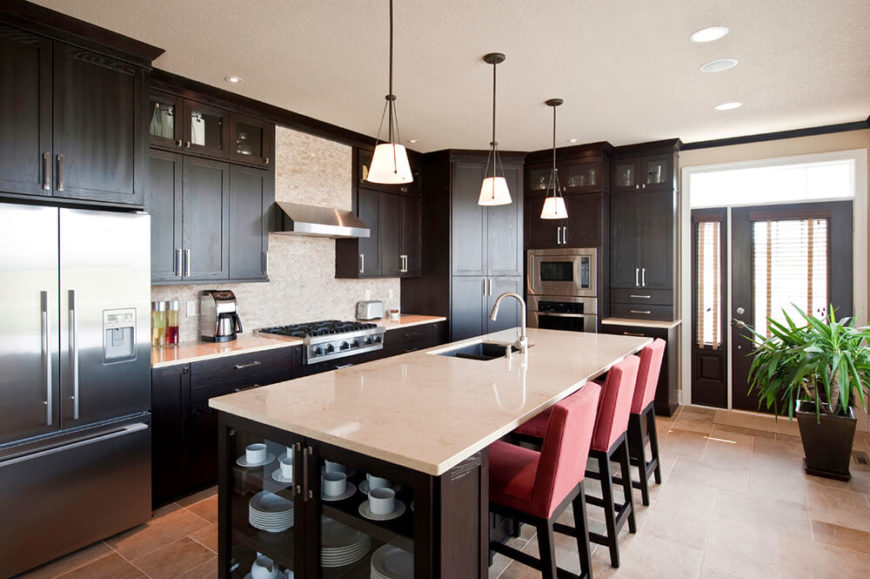 A balance of light and dark is important in narrow spaces like this. The kitchen work space is kept to a single aisle surrounded by dark cabinets but effectively balanced by the creamy countertops and matching tile backsplash. The red chairs bring a fun hint of color to the room. A balance of light and dark is important in narrow spaces like this. The kitchen work space is kept to a single aisle surrounded by dark cabinets but effectively balanced by the creamy countertops and matching tile backsplash. The red chairs bring a fun hint of color to the room.