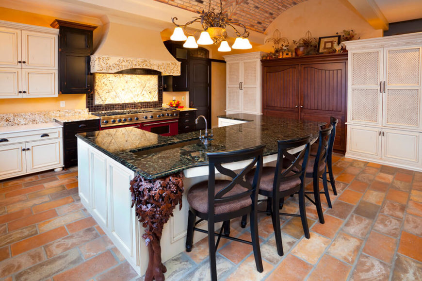 The plethora of textures in this room is reminiscent of a time gone by. The brick arched ceiling matches the colors in the bricks on the floor while white cabinets help to brighten up the space and green marble adds a bit of contrasting color. The black chairs mirror the black cabinets surrounding the stove. The plethora of textures in this room is reminiscent of a time gone by. The brick arched ceiling matches the colors in the bricks on the floor while white cabinets help to brighten up the space and green marble adds a bit of contrasting color. The black chairs mirror the black cabinets surrounding the stove.