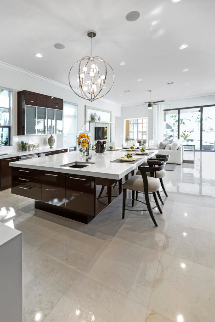 Here is a shot of the same room from the other side. You can better see the spherical pendant light above the island and the floating appearance of the cabinets. The room opens up into the living room, seen in the background. Here is a shot of the same room from the other side. You can better see the spherical pendant light above the island and the floating appearance of the cabinets. The room opens up into the living room, seen in the background.