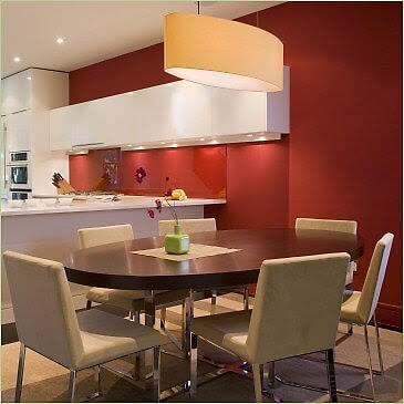 Kitchen with white cabinetry and counters along with red walls lighted by recessed lights, also featuring a dine-in table set.