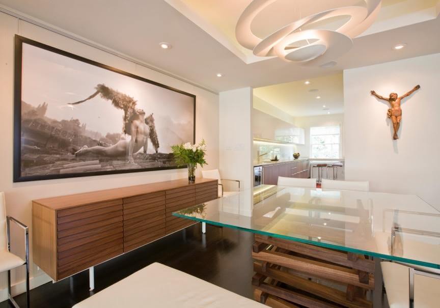 White kitchen with matching cabinetry and smooth counter lighted by recessed ceiling lights.