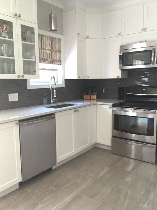 Kitchen with white cabinetry and stainless steel appliances along with tiles flooring and backsplash.