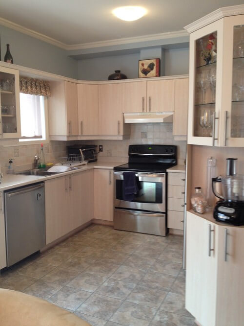 Small kitchen with wooden cabinetry and stainless steel appliances along with tiles backsplash and flooring.