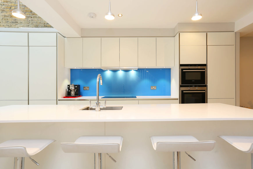 Wow factor backsplash. Bright kitchen with a cool backsplash and large center island with smooth white countertop and a space for a breakfast bar.