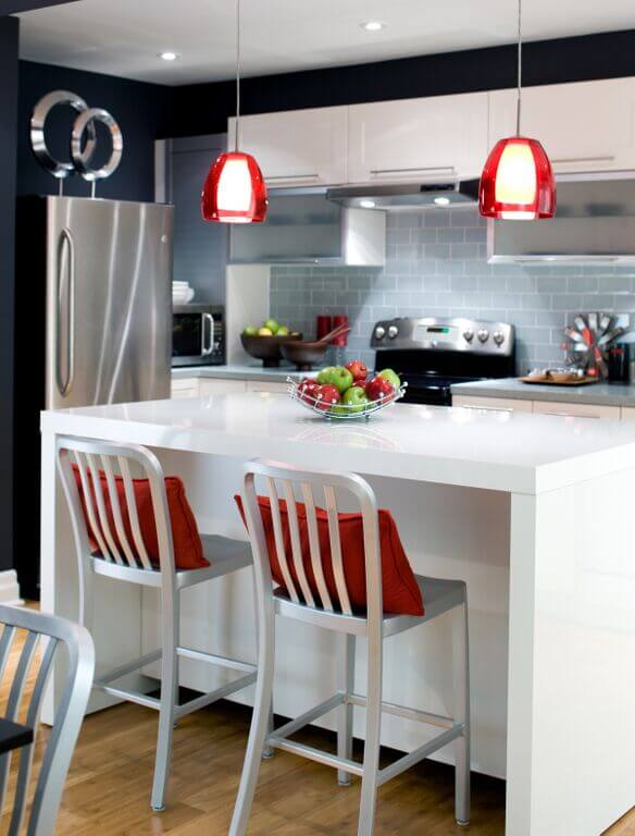 Contemporary kitchen with black walls and tiles backslash along with white cabinetry and small center island featuring a breakfast bar lighted by recessed and pendant lights.