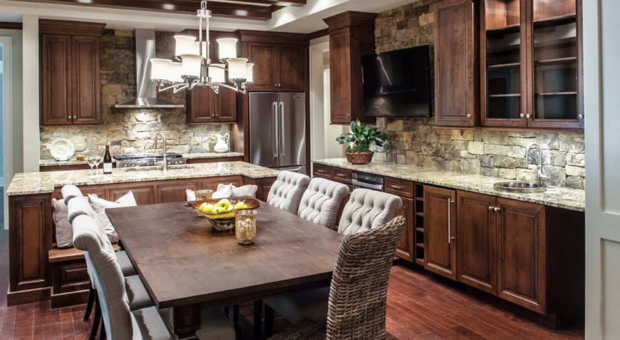 L shape kitchen with hardwood floors and wooden cabinetry along with brick backsplash and marble countertops added by a dine-in table set.