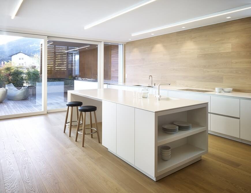 Spacious kitchen with hardwood floors and backsplash along with smooth white countertops and a large center island featuring a breakfast bar.