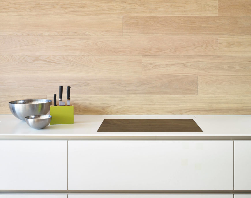 Kitchen showcasing a smooth white countertop and a wooden backsplash.