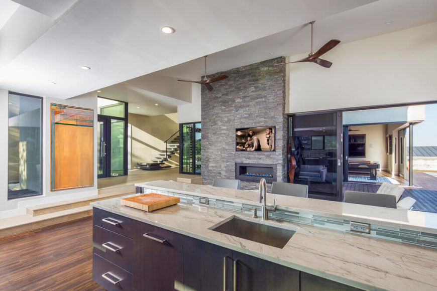 Kitchen with hardwood floors and marble countertops along with a breakfast bar lighted by recessed ceiling lights.