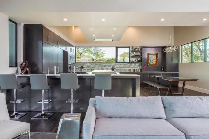 Modern large kitchen with stylish cabinetry and hardwood flooring along with a breakfast bar and a dine-in table set.