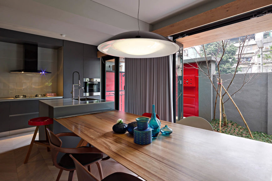 Modern kitchen with dark wood cabinetry and tiles backsplash along with a small island and a dine-in table set.