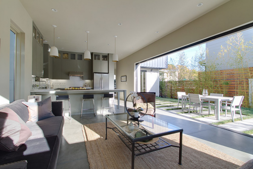 Kitchen with white walls and smooth countertops along with a breakfast bar lighted by recessed and pendant lights.