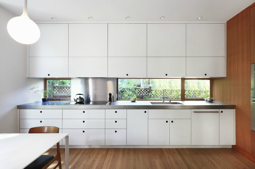 Single wall kitchen with white cabinetry and walls along with granite countertop.