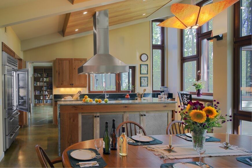 Large kitchen with yellow walls and shed ceiling along with a large center island and a dine-in table set.
