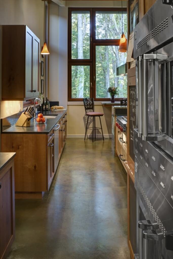 Kitchen featuring stainless steel appliances and wooden cabinetry with pendant lights and a dine-in table set.