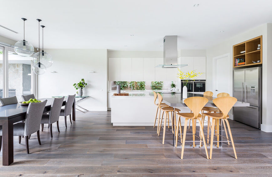 Large L shape kitchen with white walls and cabinetry along with two dine-in table sets.