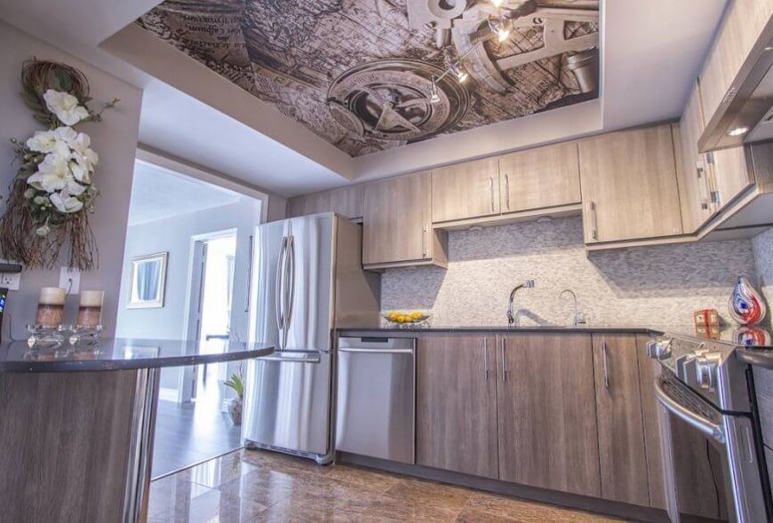 Beneath a bold art print on the ceiling of this kitchen, we see light grey stained wood cabinetry, a micro tile backsplash, and rich marble flooring. The sheen of stainless steel accents the space well. Beneath a bold art print on the ceiling of this kitchen, we see light grey stained wood cabinetry, a micro tile backsplash, and rich marble flooring. The sheen of stainless steel accents the space well.
