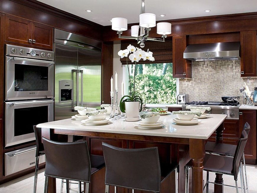 We love a solid contrast, and this cozy kitchen provides it in spades. Rich wood cabinetry pairs with white marble countertops and large stainless steel appliances for a bold mixture and striking appearance. We love a solid contrast, and this cozy kitchen provides it in spades. Rich wood cabinetry pairs with white marble countertops and large stainless steel appliances for a bold mixture and striking appearance.
