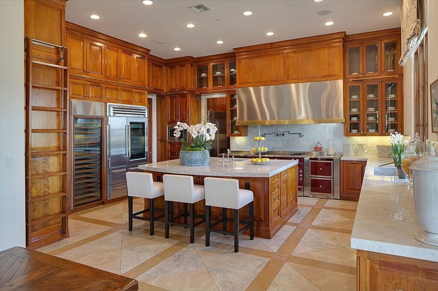 With a very tall ceiling, there's plenty of room for an abundance of warm wood cabinetry. The kitchen even features a ladder and rail system, much like a library, for reaching the upper cabinets. In addition to white marble, the space is spiked by the appearance of stainless steel appliances. With a very tall ceiling, there's plenty of room for an abundance of warm wood cabinetry. The kitchen even features a ladder and rail system, much like a library, for reaching the upper cabinets. In addition to white marble, the space is spiked by the appearance of stainless steel appliances.