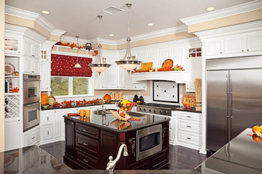 The warmly traditional look of this kitchen is slightly offset by the appearance of stainless steel appliances, adding a flash of the modern. The dark wood island at center features a built-in microwave, storage, and sink, offering utility and a visual anchor to the room. The warmly traditional look of this kitchen is slightly offset by the appearance of stainless steel appliances, adding a flash of the modern. The dark wood island at center features a built-in microwave, storage, and sink, offering utility and a visual anchor to the room.