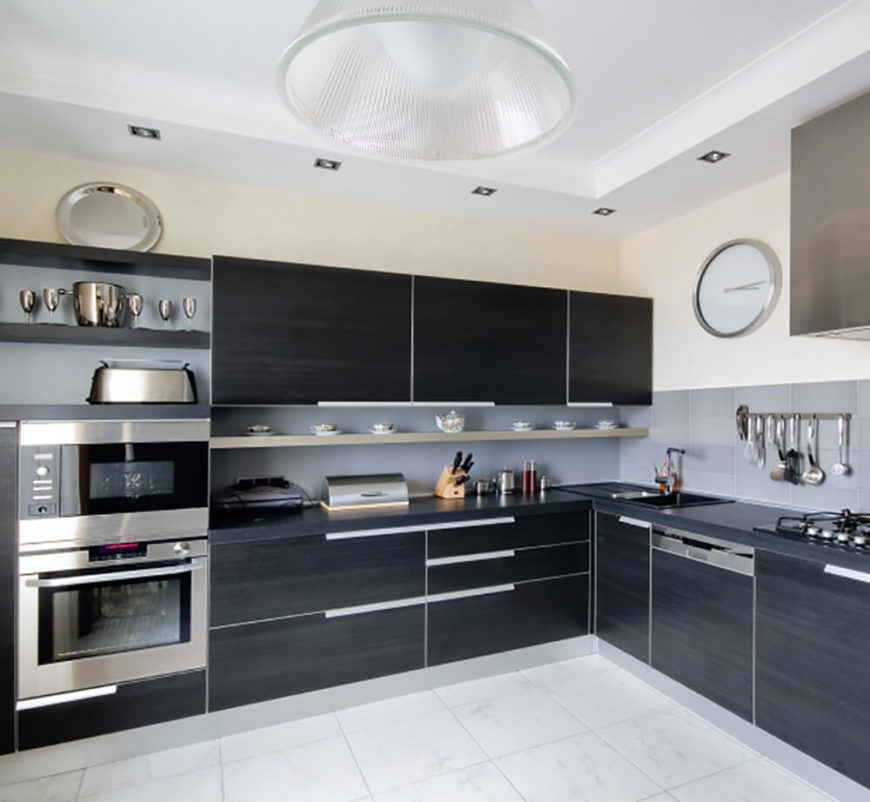 Stark black cabinetry and stainless steel appliances mesh for a sleek look in this thoroughly contemporary kitchen. Large format marble tile flooring and a grey backsplash keep the neutral tone. Stark black cabinetry and stainless steel appliances mesh for a sleek look in this thoroughly contemporary kitchen. Large format marble tile flooring and a grey backsplash keep the neutral tone.