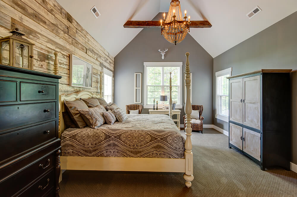 A very attractive primary bedroom featuring gray walls and vaulted ceiling lighted by a glamorous chandelier.