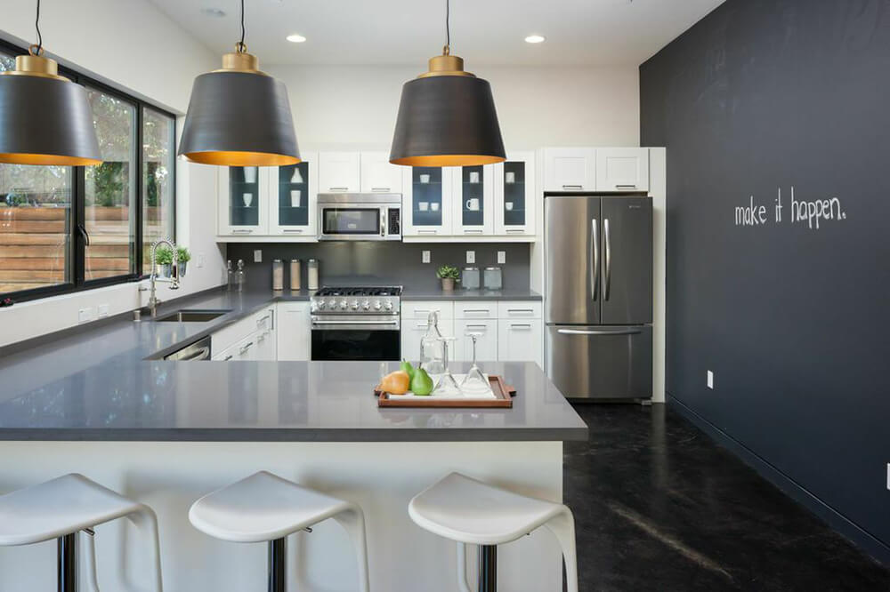 Stylish kitchen with a gray wall matching the counters' countertops. The pendant lights look stylish along with the dark-finished flooring.
