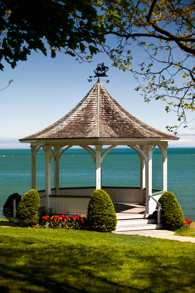 A seaside gazebo flanked by evergreen topiaries and bold red flowers. The view from this structure is gorgeous. Truly a center of outdoor entertaining. A seaside gazebo flanked by evergreen topiaries and bold red flowers. The view from this structure is gorgeous. Truly a center of outdoor entertaining.